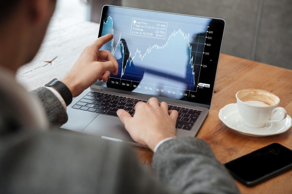 Man sitting by the table in cafe and analyzing indicators on laptop